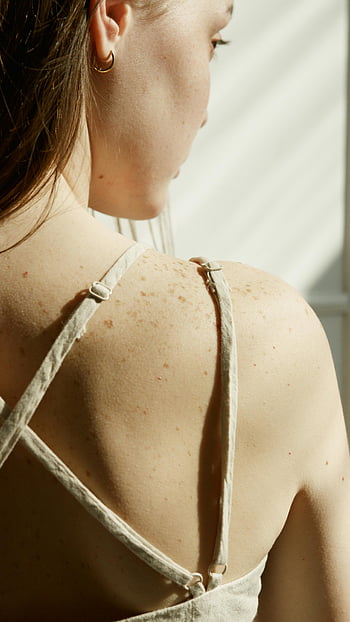 woman's back, close-up shot, freckled skin, natural sunlight, skin details, back view, woman's shoulders, sunlight bathed, freckles, back straps, natural light