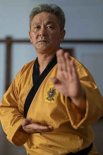 uomo anziano, arti marziali, gi tradizionale, Pratica interna, espressione focalizzata, sguardo determinato, gi giallo, cintura nera, Allenamento al chiuso, artista marziale senior, Pratica del karate