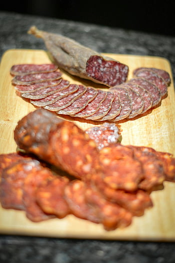 smoked sausages, sliced sausages, cutting board, cured meats, rustic wooden board, culinary presentations, sliced meats, smoked meats, meat presentation, food photography, charcuterie board