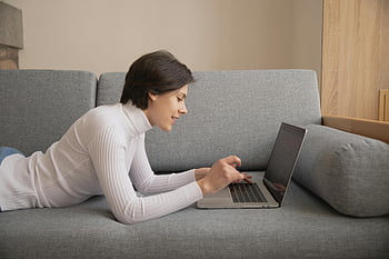 žena pomocí přenosného počítače, vzdálené práce, ležet na pohovce, domácí kancelář, pracování z domova, notebook na gauči, Pohodlný pracovní prostor, příležitostné pracovní prostředí, Žena pracuje na dálku, domácí práce, Útulné nastavení práce