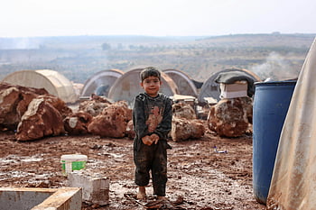 chlapeček, zablácený uprchlický tábor, Idlib Sýrie, provizorní stany, skalnatý terén, mladý kluk, uprchlický tábor, zablácený terén, Humanitární krize, vysídlené dítě, humanitární pomoc