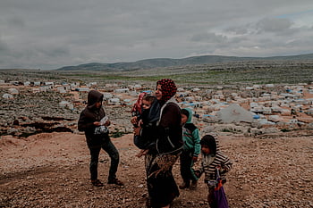 Muslimská matka, dítě v náručí, děti kolem, uprchlický tábor, Idlib Sýrie, rodinné procházky, Etnická matka, Rodina uprchlíků, Syrští uprchlíci, Humanitární krize, Krize posunu