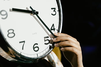 analog clock, white clock, hand adjusting clock, bold numbers, large clock, quartz clock, time adjustment, clock face, analog timepiece, clock hands, person holding clock