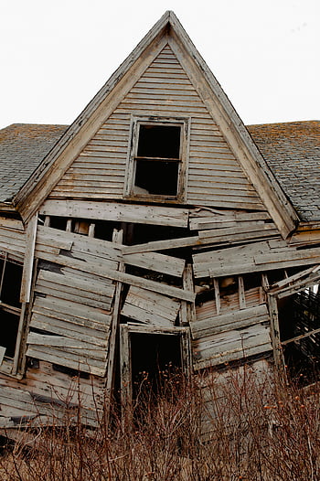 old wooden house, derelict house, decay, disrepair, haunting image, abandoned house, weathered wood, broken windows, overgrown vegetation, rustic architecture, dilapidated building