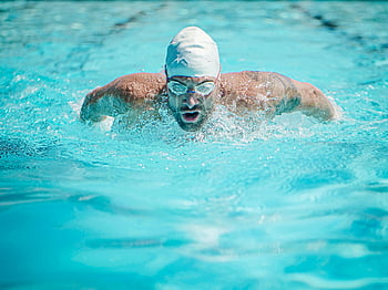 man wearing goggles, swimming fast, focused swimmer, vibrant turquoise pool, athletic prowess, dedication, swimmer stroke, competitive swimming, water sport, swimmer performance, pool exercise