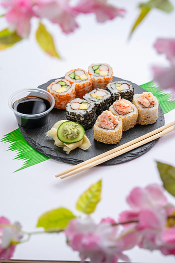 Sushi-Platte, Essstäbchen, Sojasauce, Wasabi, farbenfrohe Blumen, Leckeres Sushi, Essen auf dem Tisch, Sushi Rollen, japanische Küche, Esstisch, Blumendekoration