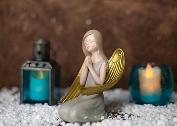 andělská figurka, zlatá křídla, svíčka, klidné prostředí, teplé nastavení, okouzlující anděl, detailní záběr, Dekorativní figurka, duchovní výzdoba, domovní dekorace, socha anděla