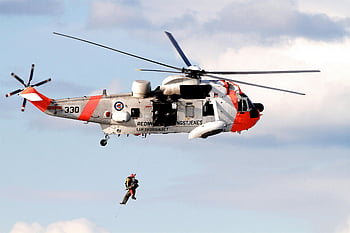 rescue helicopter, Royal Norwegian Air Force, hoist operation, mid-air, clear day, white and orange helicopter, air rescue, military helicopter, emergency operation, Norwegian Air Force, hoist rescue