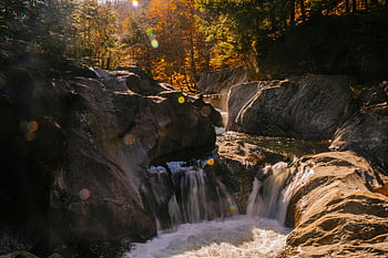 waterfall, flowing water, rocky terrain, autumn forest, lush foliage, serene landscape, natural scenery, outdoor beauty, cascading water, forest stream, seasonal colors