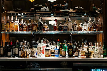liquor bottles, bar shelf, well-lit bar, diverse collection, alcohol bottles, bar display, glass shelves, bar setting, bottle showcase, bar interior, bar ambiance
