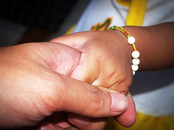 adult holding child's hand, close-up hands, love and support, family connection, child's hand, adult hand, bracelet, emotional bond, tender moment, togetherness, care