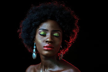 nő bezárja a szemét, elegáns portré, afro haj, élénk szemhéjpúder, vörös ajkak, fekete háttér, elegáns fülbevalók, természetes szépség, elbűvölő megjelenés, sötét bőr, csukott szemmel