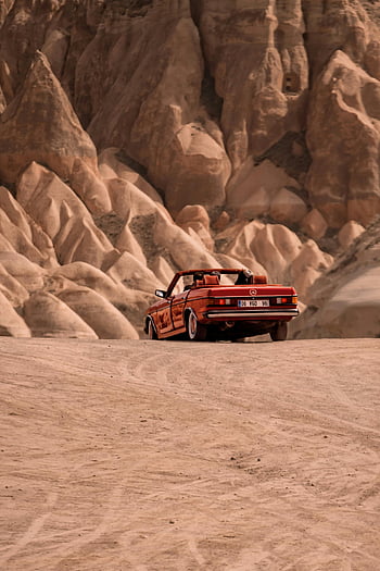 red cabrio car, desert driving, Cappadocia rocky terrain, Nevşehir, Türkiye, convertible car, unique landscape, red car, rocky desert, travel destination, scenic drive