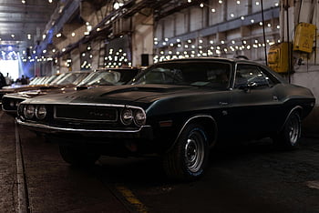 black muscle car, vintage Dodge Challenger, industrial garage, classic car, nostalgia, car elegance, parking garage, black Dodge, vintage car, garage setting, muscle car