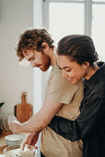 woman hugging man, joyful couple, preparing breakfast, cozy kitchen, couple embracing, kitchen scene, morning routine, domestic life, happy couple, intimate moment, home cooking