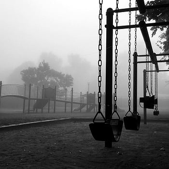black metal swing, black and white photo, empty swings, foggy park, eerie atmosphere, playground equipment, misty morning, outdoor scene, monochrome image, abandoned playground, silent park