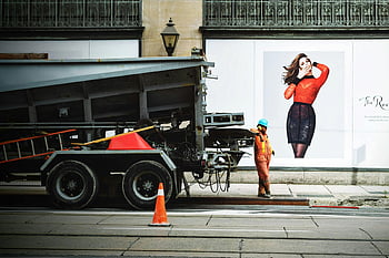 construction worker, orange safety suit, truck bed, city street, safety cone, urban setting, work attire, industrial vehicle, street scene, safety gear, sidewalk