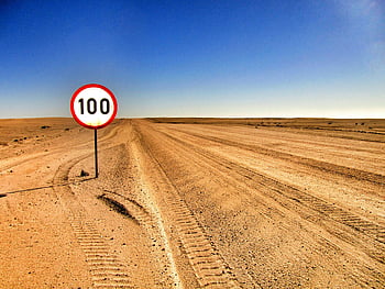 desert road, speed limit sign, 100 km/h, clear sky, open road, road signage, desert landscape, tire tracks, speed limit, road sign, desert environment