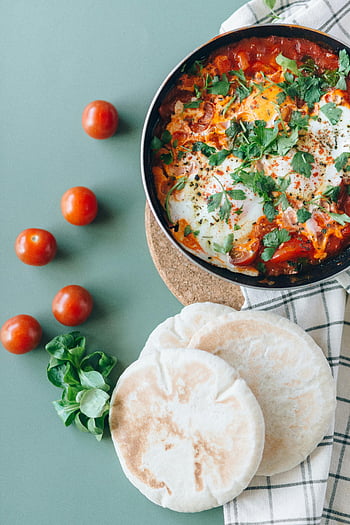 shakshuka, pita bread, green table, top view, herbs, tomatoes, breakfast, Middle Eastern cuisine, food photography, flatbread, skillet
