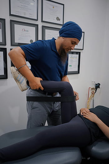 physiotherapist, leg rehabilitation, male physiotherapist, turban, female patient, modern clinic, leg exercise, physical therapy, clinic setting, rehabilitation exercise, leg treatment