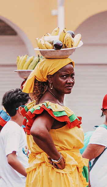 Colombian fruit vendor, traditional attire, vibrant dress, street vendor, balancing fruit, colorful portrait, Colombian culture, traditional clothing, fruit on head, street scene, cultural heritage