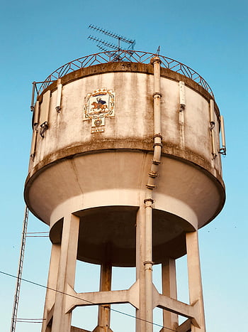 water tower, concrete, white and brown, clear sky, green and blue sky, large structure, antennas, outdoor, infrastructure, architecture, utility