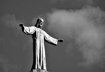 Jesus Christ statue, black and white photo, cloudy sky, reaching out, religious statue, monochrome image, outdoor sculpture, spiritual figure, Christian icon, faith symbol, art installation
