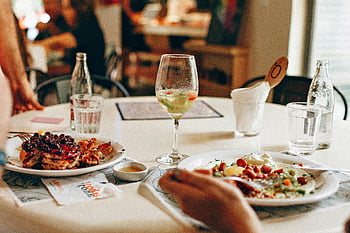wine in clear glass, food on plate, pancakes with berries, brunch, dining experience, table setting, delicious meal, breakfast, restaurant scene, dining table, wine glass