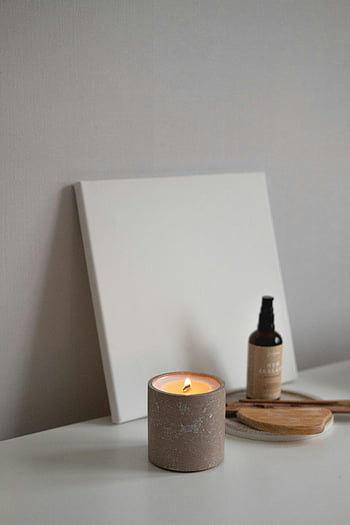 candela accesa, tela vuota, Scena minimalista, Atmosfera calmante, Olio essenziale, tela bianca, superficie di legno, impostazione serena, olio aromatico, arredamento minimalista