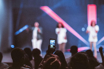 Videongaing smartphone, koncert, mělké zaměření, členové publika, živá hudba, Vibrující jevištní světla, zachycení koncertu, hudební událost, Jevištní umělci, koncertní fotografie, nahrávání smartphone