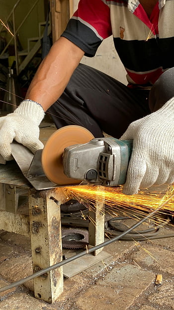 metalworker, grinder, cutting metal, sparks, industrial workshop, skillful, metal product, gloves, workshop setting, metal grinding, artisan