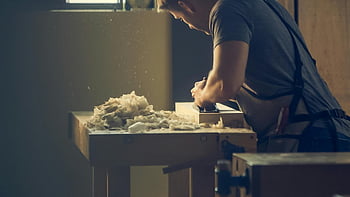 Handwerker, Holz formen, Workshop Bank, Holzspäne, Mann stehend, vor dem Tisch, Holzbearbeitung, erfahrener Handwerker, Workshop -Szene, Holzarbeitsprozess, Zimmermannswerkzeuge