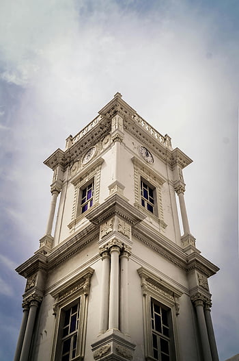 Victorian-style clock tower, historic architecture, low angle view, ornate building, cloudy sky, white and gray building, Victorian architecture, clock tower, historic building, ornate design, cloudy day