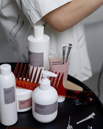 hair cosmetics, black surface, haircare products, shampoos, conditioners, combs, smoothing mask, restorative hair mask, renewing conditioner, neatly arranged, table