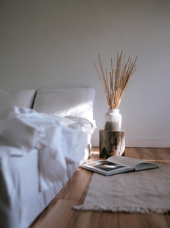 Camera da letto accogliente, camera da letto minimalista, biancheria da letto bianca, bouquet secco, libro sul pavimento, Luce naturale morbida, pavimento di legno, vaso bianco, arredamento rustico, interni accoglienti, arredamento minimalista