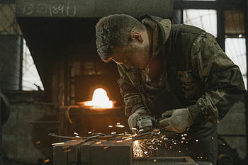 blacksmith, protective gear, grinding machine, sparks, forge, metalwork, industrial, craftsmanship, workshop, fire, safety equipment