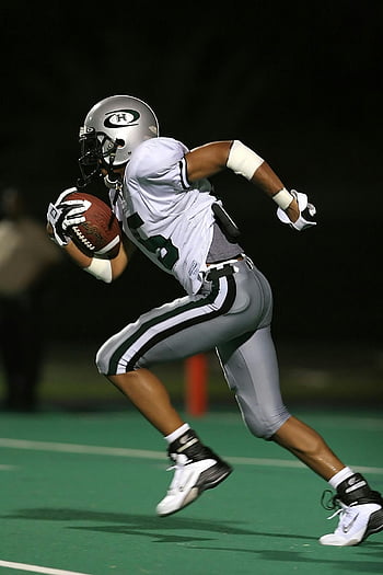 football player, holding football, high-speed capture, running, field, night game, athleticism, sports action, football uniform, green field, night sports