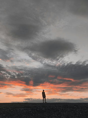 sunset silhouette, man silhouette, vibrant sky, nature beauty, gray sky, lone figure, sunset clouds, outdoor scene, dramatic sky, peaceful moment, natural landscape