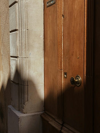 brown wooden door, brass door knob, close-up, wooden door, brass knob, shadows, stone facade, architectural detail, vintage door, door hardware, sunlight