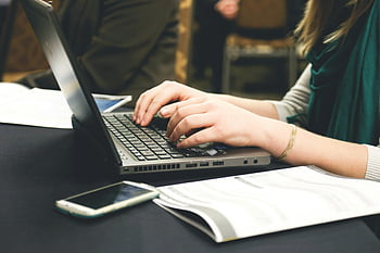 kvinde typing, bærbar, hænder på tastaturet, arbejdsområde, skrivebord, smartphone, papirer, indendørs indstilling, Fokuseret arbejde, fagligt miljø, Teknologibrug