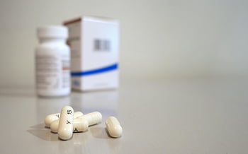 medication pills, white capsules, close-up image, medicine bottle, box background, oblong pills, pharmaceutical products, healthcare items, medical treatment, prescription drugs, pharmacy items