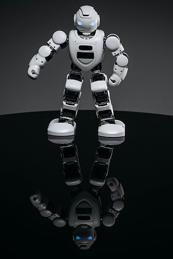 white robot toy, black surface, futuristic robot, reflective surface, dark background, small robot, toy robot, robot figure, white toy, black background, futuristic design