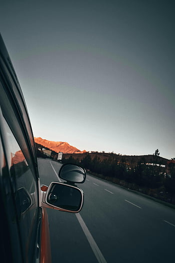 luxury car, side mirror, mountain road, dusk, distant scenery, vehicle reflection, road view, car window, grey vehicle, side mirror reflection, mountain landscape