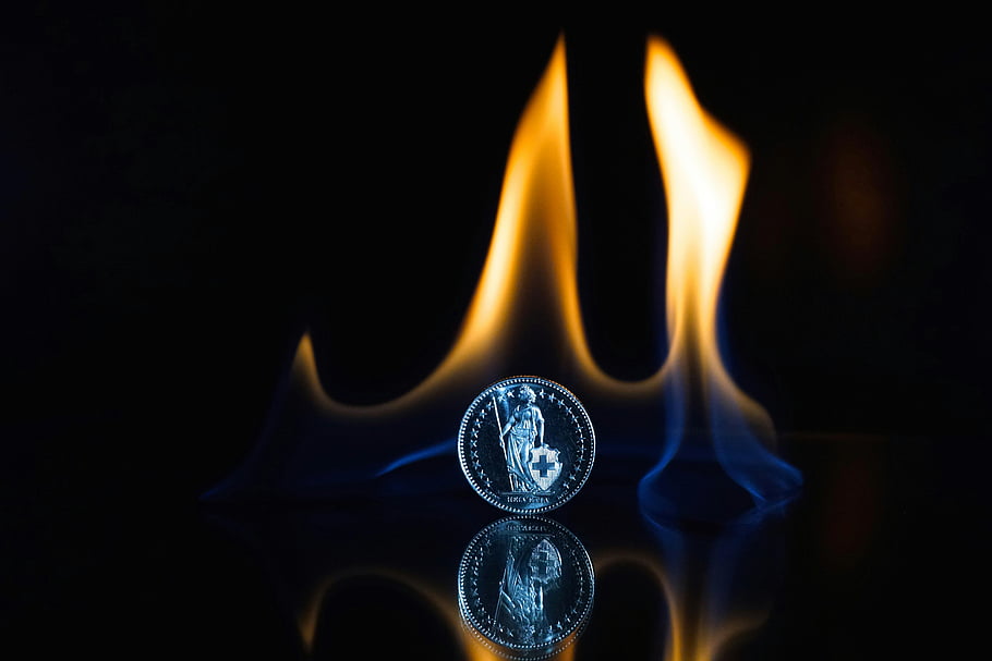 moneta, superficie nera, fiamma, superficie riflettente, arte astratta infuocata, fiamme drammatiche, moneta tonda, moneta color argento, sfondo nero, fotografia di monete, arte del fuoco