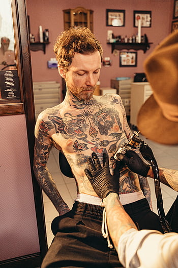 Nackter Oberkörper Mann, tätowieren, Brusttattoo, Tattoo-Studio, künstlerisches Ambiente, Tattoo-Künstler, Tätowierungsprozess, Körperkunst, Studioeinstellung, männliche Tätowierung, tätowierter Mann