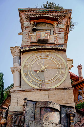 Krzywa Wieża w Tbilisi, wieża zegarowa, unikalna architektura, Tbilisi, pochylająca się struktura, styl architektoniczny, Intrygująca wieża, cyfry rzymskie, Dekoracyjne kolumny, dzwonnica, scena plenerowa