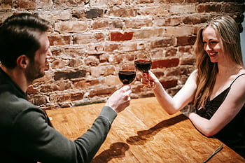antic dinner, couple toasting, red wine, cozy restaurant, romantic evening, wineglasses, brick wall, intimate setting, romantic atmosphere, couple enjoying, romantic moment