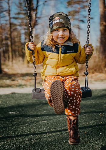 child on swing, smiling child, yellow jacket, autumn day, outdoor play, bright day, happiness, kid swinging, playground, fall season, children's clothing