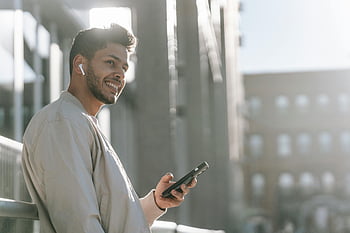 szczęśliwy człowiek, smartfon, ulica, słuchawki douszne, uśmiechnięty, na dworze, muzyka, nowoczesny styl życia, młody człowiek, porozumiewanie się, technologia