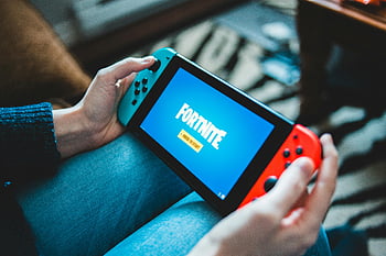 nintendo kapcsoló, fortnite játék, kéz tartja, Játék Konzol, beltéri környezet, közeli fotó, játékeszköz, hordozható játék, videojáték -képernyő, játékvezérlő, szórakoztató eszköz